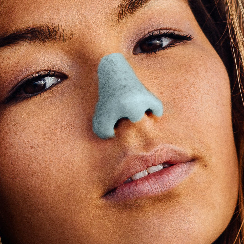 NӦZ sunscreen in the colorful shade light blue being worn on the nose of a woman